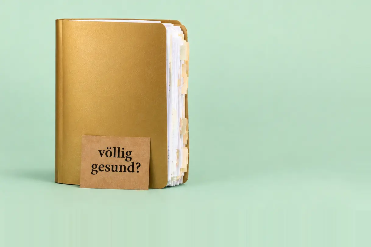 Ich bin völlig gesund: prall gefüllte goldene Krankenakte mit einem Schild völlig gesund